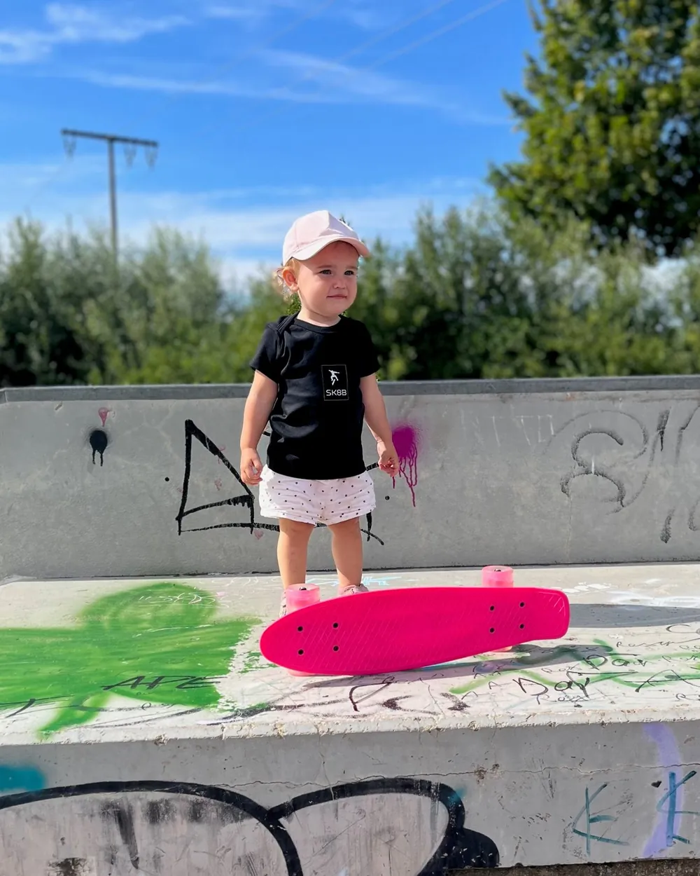 Kleines Mädchen mit pinkem Skateboard im Skatepark Burgau